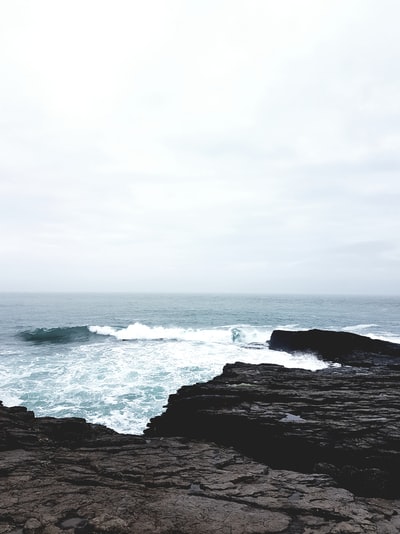 海浪撞在岩石上在白天多云的天空下
